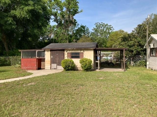 exterior space with an outdoor structure, a carport, and a front yard