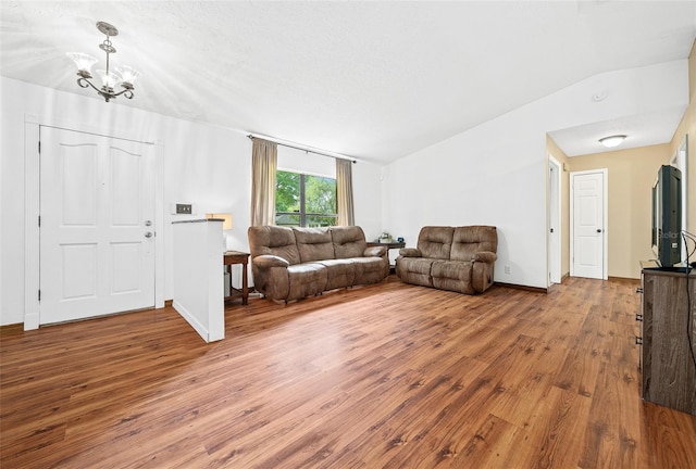 living room with an inviting chandelier, wood-type flooring, and lofted ceiling