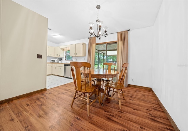 dining room with lofted ceiling, light tile flooring, and a notable chandelier