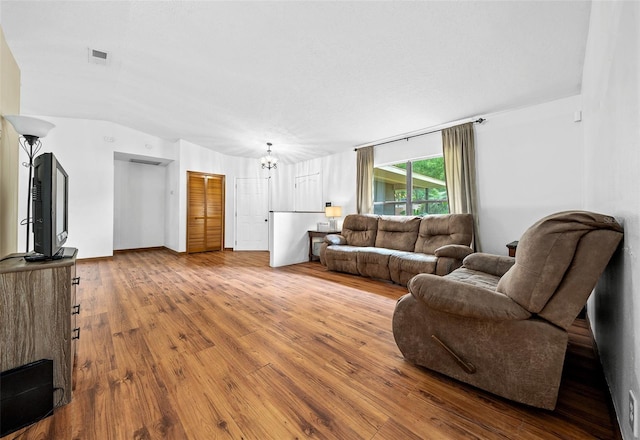 living room featuring hardwood / wood-style floors, vaulted ceiling, and a chandelier