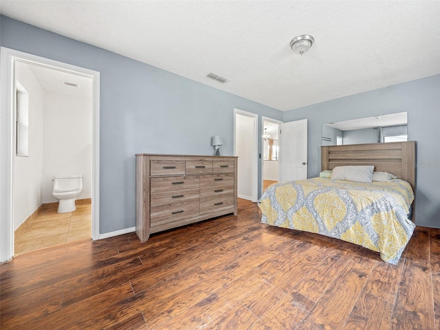 bedroom with ensuite bathroom and hardwood / wood-style flooring