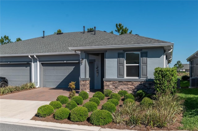 ranch-style home with a garage and central air condition unit