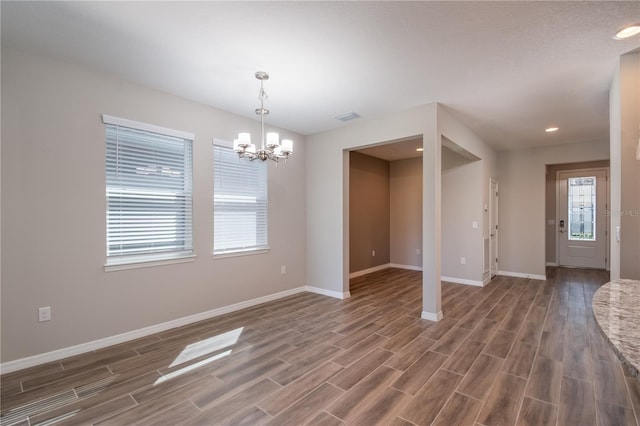 unfurnished room with an inviting chandelier and dark hardwood / wood-style floors