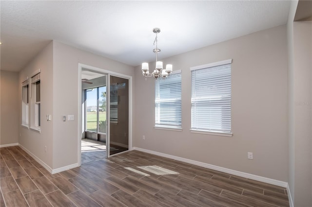 empty room with a textured ceiling, an inviting chandelier, and dark hardwood / wood-style flooring