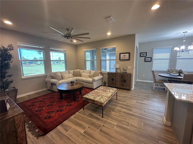 living room featuring hardwood / wood-style flooring and ceiling fan with notable chandelier