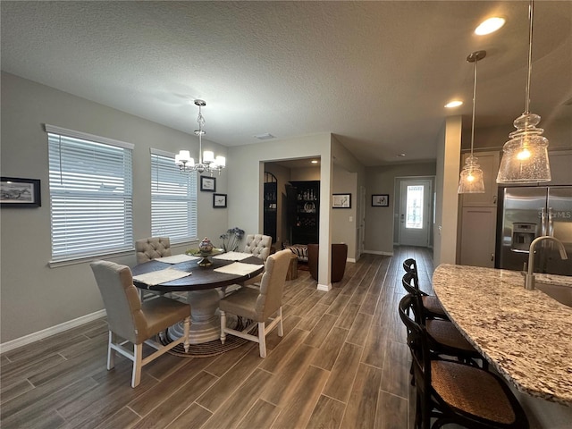 dining space featuring a notable chandelier, dark hardwood / wood-style floors, a textured ceiling, and sink