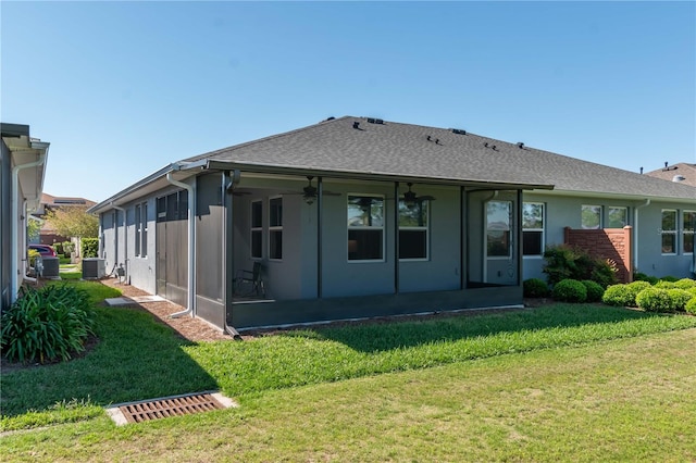 back of house featuring a sunroom, a lawn, and central AC unit