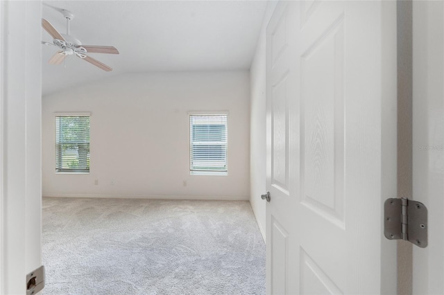 spare room with light colored carpet, a wealth of natural light, lofted ceiling, and ceiling fan