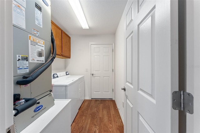 laundry room with cabinets, dark hardwood / wood-style flooring, a textured ceiling, heating unit, and washer and dryer