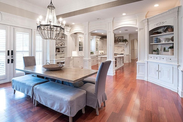 dining area with a notable chandelier, built in features, ornamental molding, dark hardwood / wood-style flooring, and decorative columns