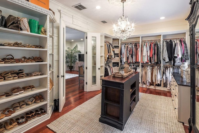 spacious closet with dark hardwood / wood-style flooring and a notable chandelier