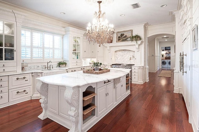 kitchen with washing machine and dryer, a kitchen island, decorative light fixtures, white cabinetry, and dark hardwood / wood-style flooring