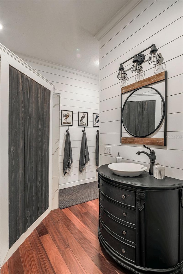 bathroom with wood walls, ornamental molding, wood-type flooring, and vanity