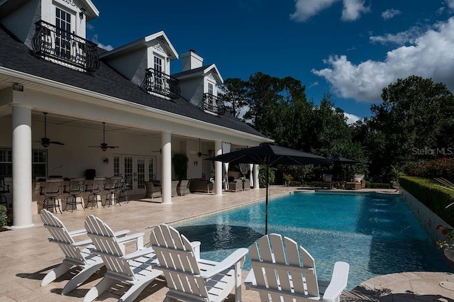 view of swimming pool featuring ceiling fan, french doors, an outdoor bar, and a patio area