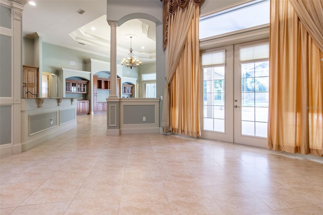 empty room featuring a high ceiling, french doors, crown molding, a tray ceiling, and a notable chandelier