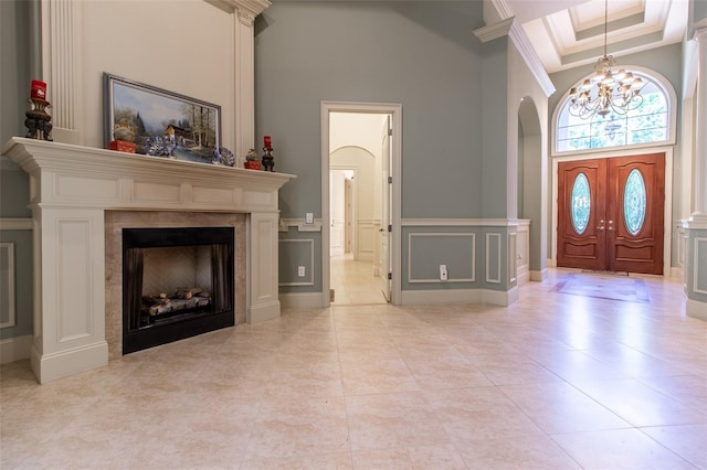 tiled foyer featuring a towering ceiling, crown molding, and a notable chandelier