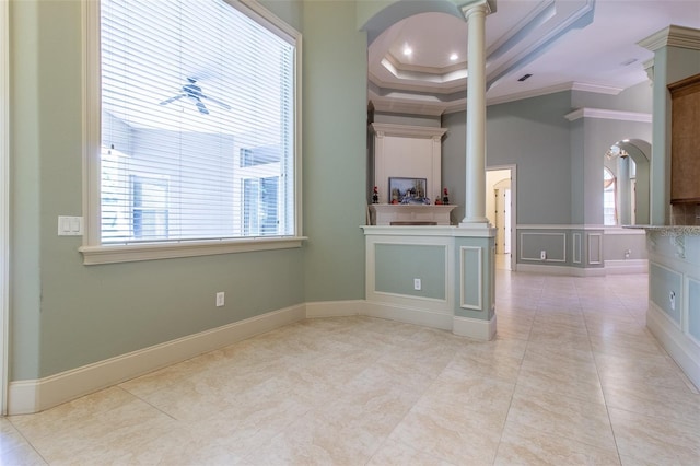 empty room with a tray ceiling, ornate columns, crown molding, and light tile patterned floors