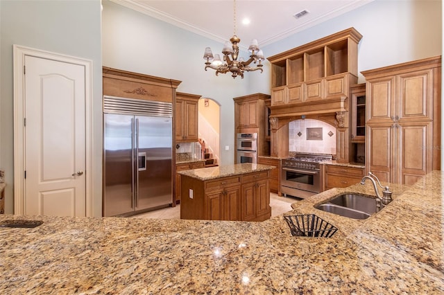 kitchen with high quality appliances, sink, light stone countertops, decorative light fixtures, and a chandelier