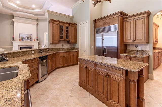 kitchen with light stone countertops, backsplash, stainless steel appliances, crown molding, and light tile patterned floors