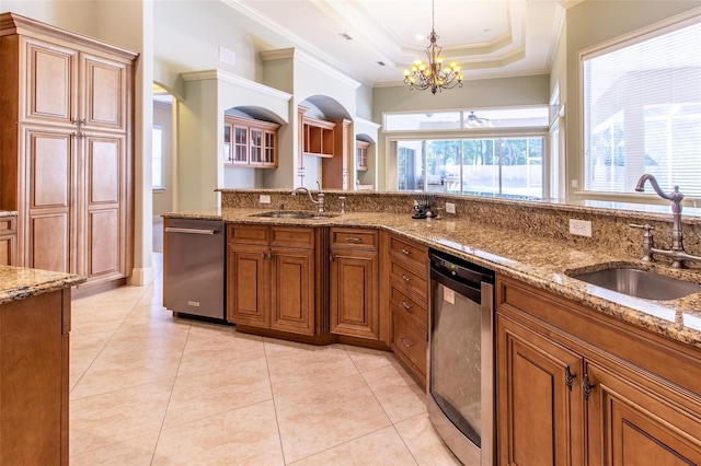 kitchen with a raised ceiling, dishwasher, an inviting chandelier, and sink