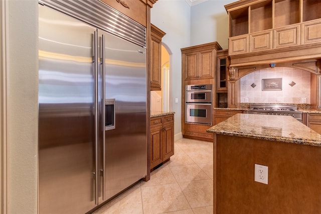 kitchen featuring decorative backsplash, a center island, light stone countertops, and appliances with stainless steel finishes