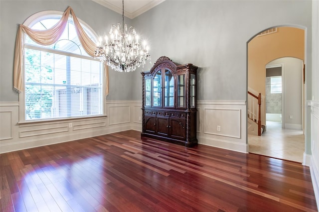 empty room with dark hardwood / wood-style flooring, an inviting chandelier, and crown molding