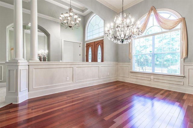 interior space featuring decorative columns, hardwood / wood-style floors, a chandelier, and ornamental molding