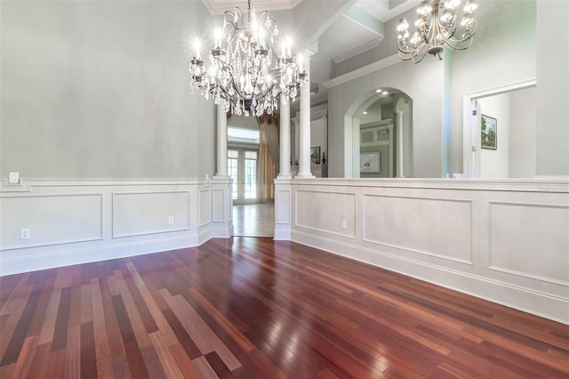 unfurnished dining area with a chandelier, dark wood-type flooring, and decorative columns