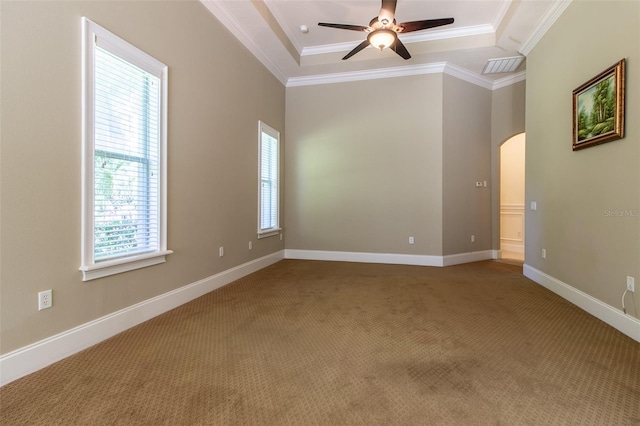 carpeted spare room featuring a tray ceiling, a healthy amount of sunlight, and ornamental molding