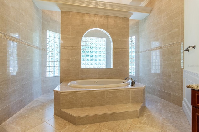 bathroom featuring vanity, a relaxing tiled tub, and tile walls