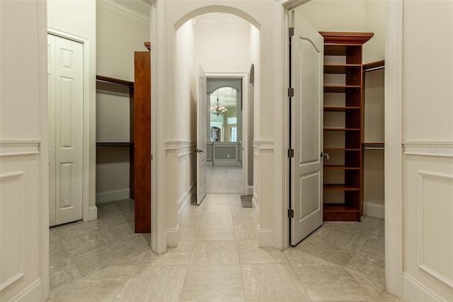 corridor featuring light tile patterned floors, an inviting chandelier, and crown molding