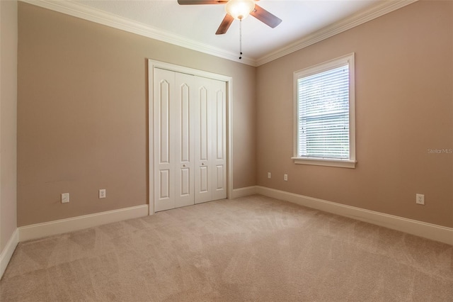 unfurnished bedroom featuring a closet, ceiling fan, crown molding, and light carpet