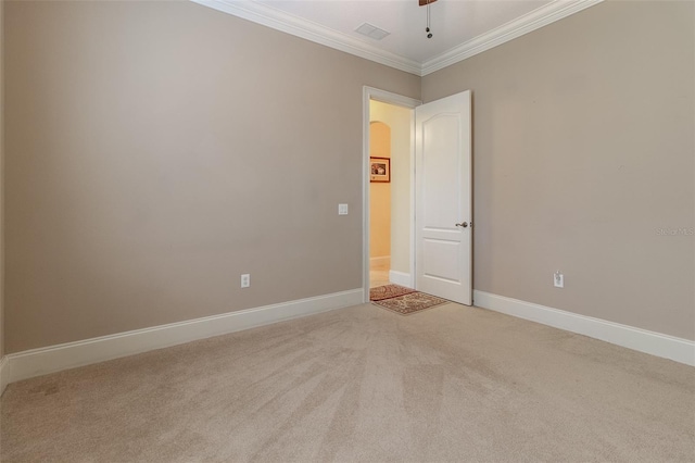 empty room with ceiling fan, crown molding, and light carpet