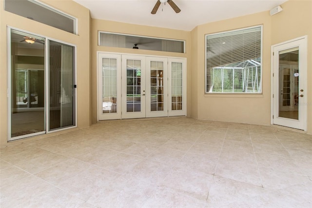 unfurnished sunroom featuring ceiling fan and french doors