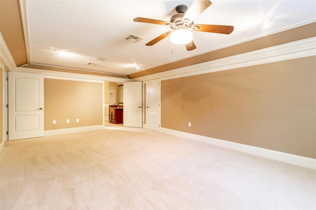 spare room with ceiling fan, light colored carpet, and crown molding