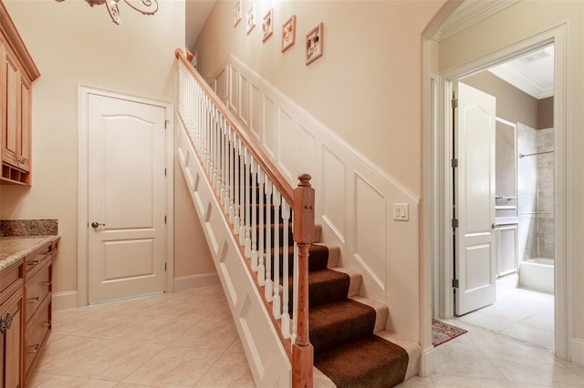 stairs with tile patterned flooring, crown molding, and a chandelier