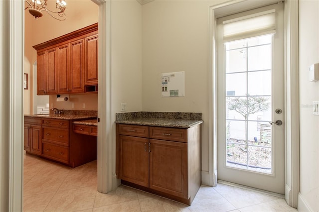 kitchen featuring light tile patterned floors, dark stone counters, and a chandelier