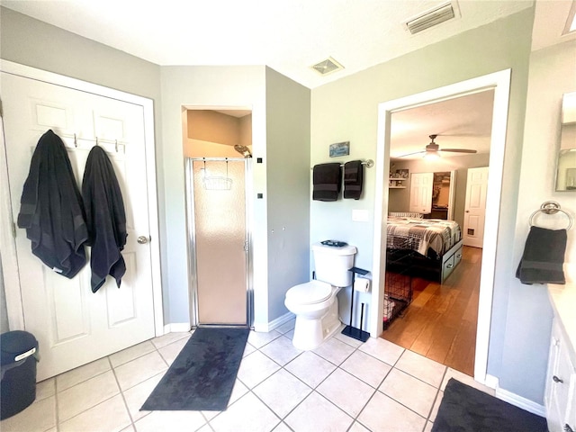 bathroom featuring wood-type flooring, toilet, ceiling fan, and a shower with shower door