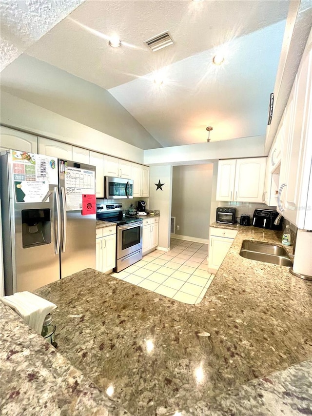 kitchen featuring lofted ceiling, backsplash, sink, appliances with stainless steel finishes, and white cabinetry