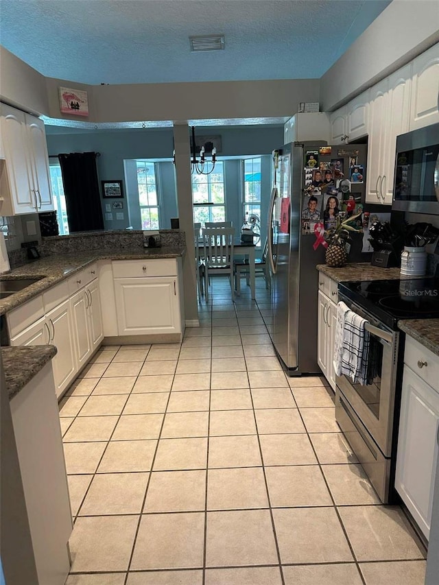 kitchen featuring a chandelier, appliances with stainless steel finishes, white cabinetry, and light tile patterned flooring