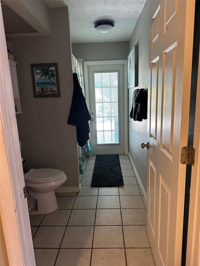 bathroom with tile patterned flooring, toilet, and a textured ceiling