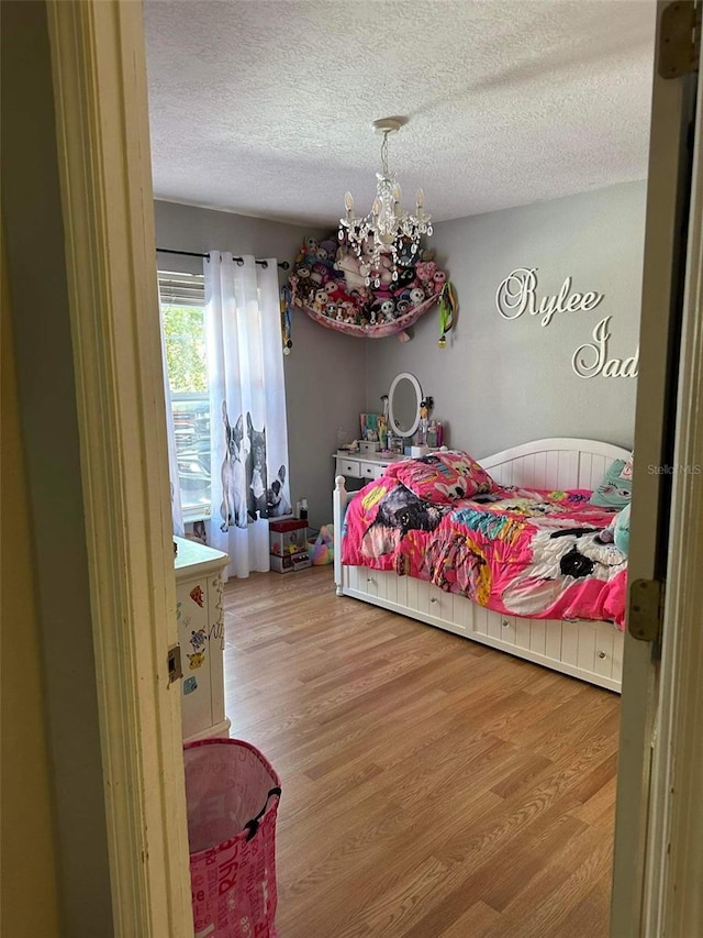 bedroom featuring hardwood / wood-style floors, a textured ceiling, and a notable chandelier