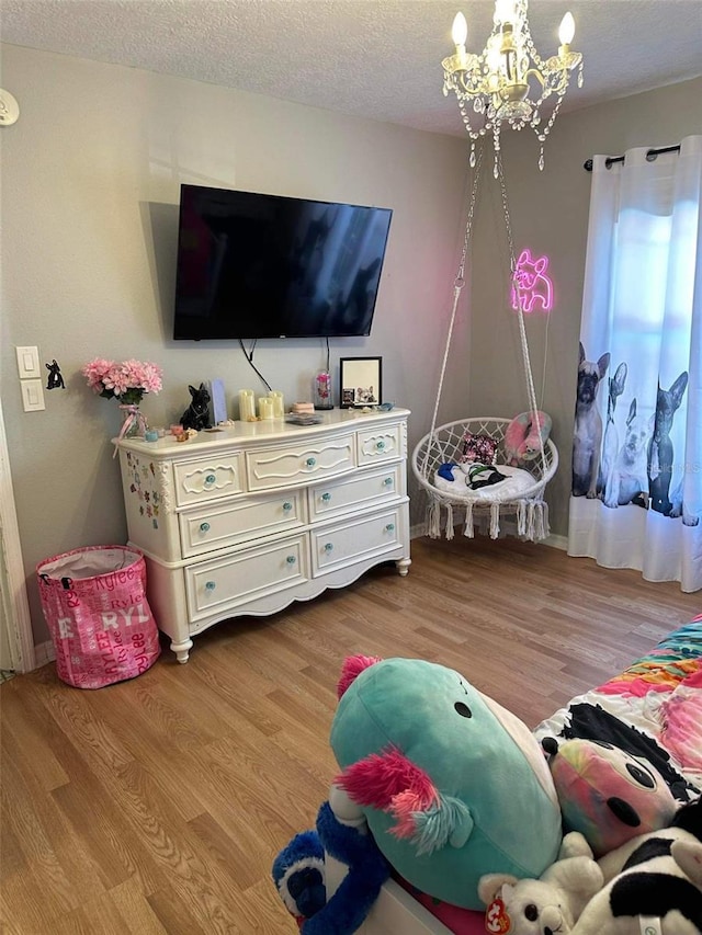 rec room featuring a notable chandelier, a textured ceiling, and light hardwood / wood-style flooring