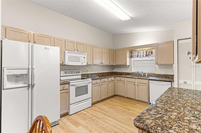 kitchen featuring sink, vaulted ceiling, a textured ceiling, white appliances, and light brown cabinetry