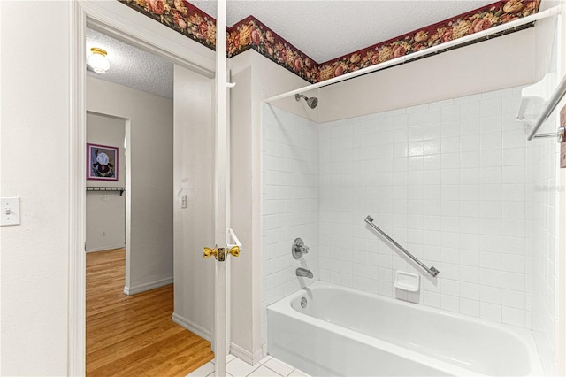 bathroom featuring a textured ceiling, hardwood / wood-style flooring, and tiled shower / bath combo