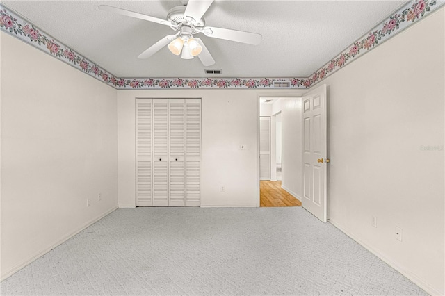 unfurnished bedroom with ceiling fan, light colored carpet, a textured ceiling, and a closet