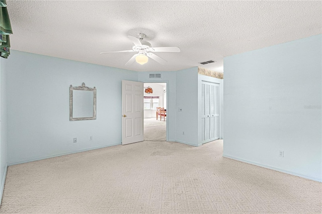 unfurnished room featuring light carpet, a textured ceiling, and ceiling fan