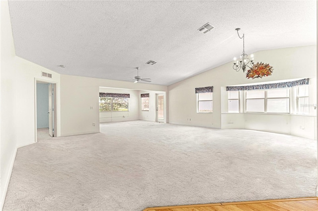 unfurnished living room with a textured ceiling, ceiling fan with notable chandelier, and lofted ceiling