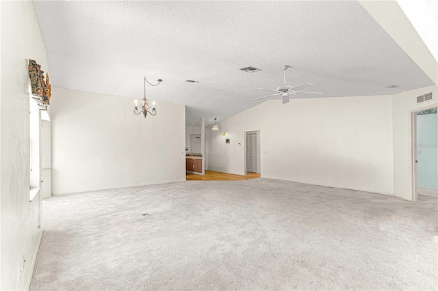 carpeted spare room featuring a textured ceiling, ceiling fan with notable chandelier, and vaulted ceiling