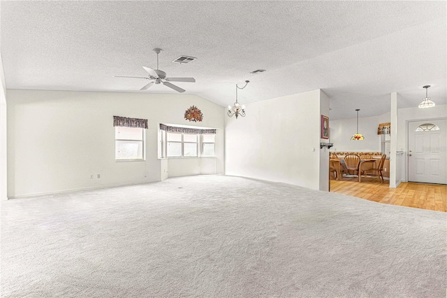 spare room featuring light carpet, a textured ceiling, ceiling fan with notable chandelier, and vaulted ceiling